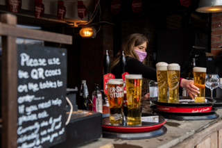 Woman serving drinks outside as the lockdown roadmap goes ahead in England