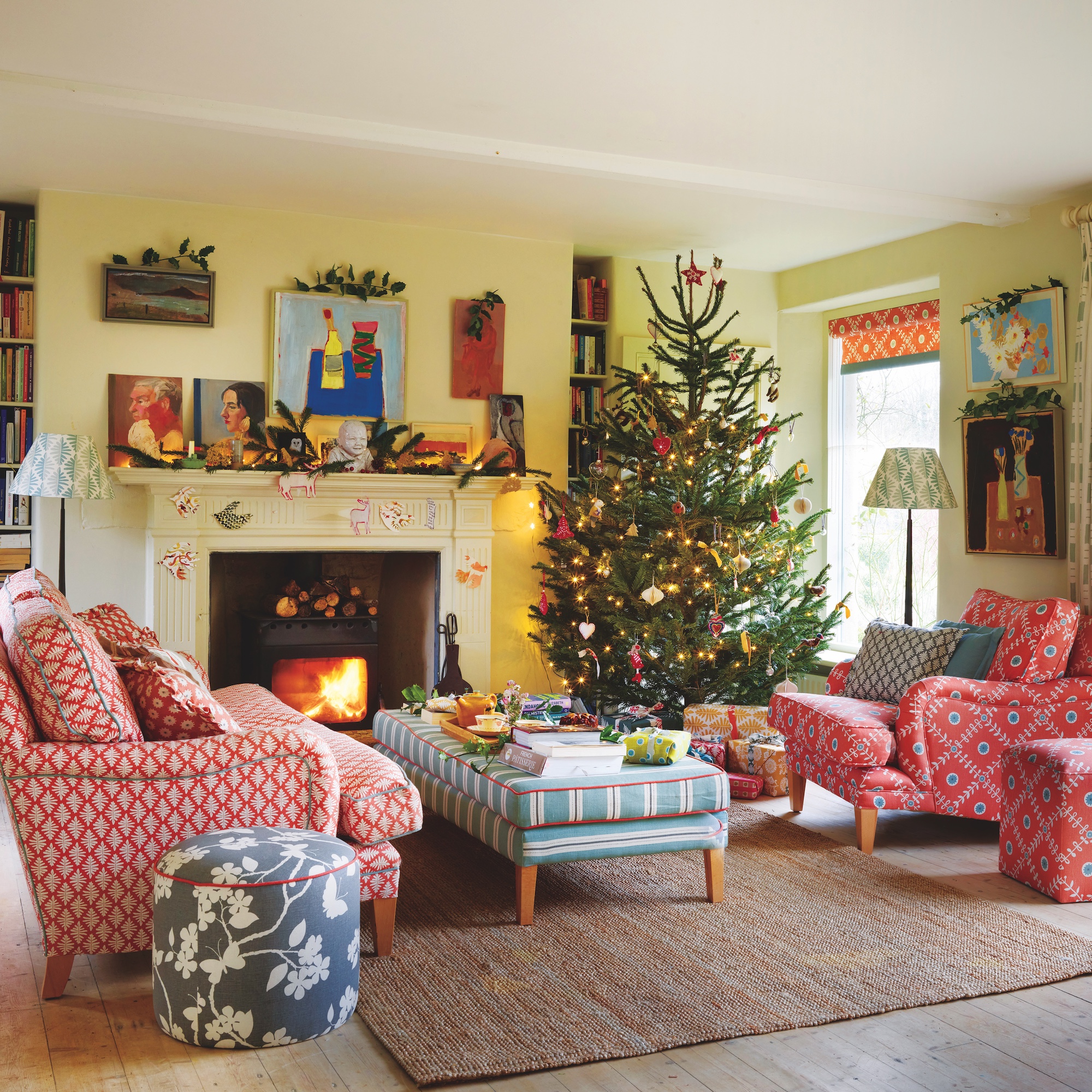 chairs and upholstered footstool in front of a fireplace with woodburning stove, in a room decorated with a Chrsitmas tree