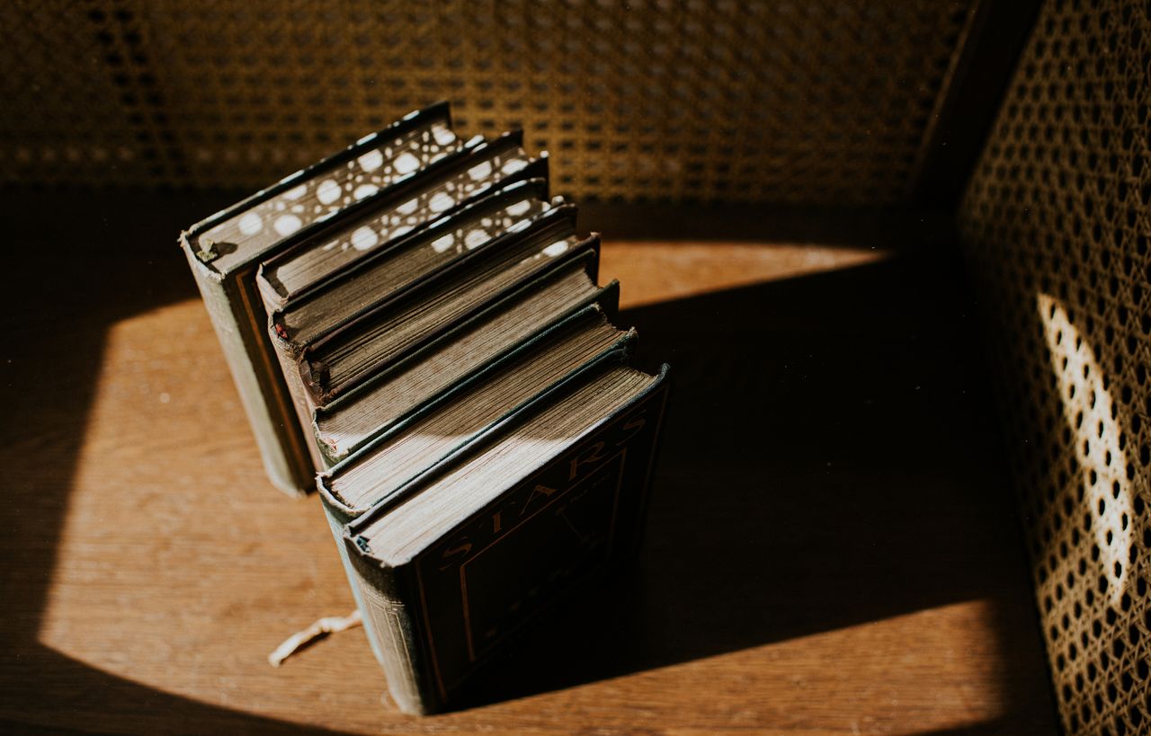 Overhead view of several old books in sunlight on a wooden surface