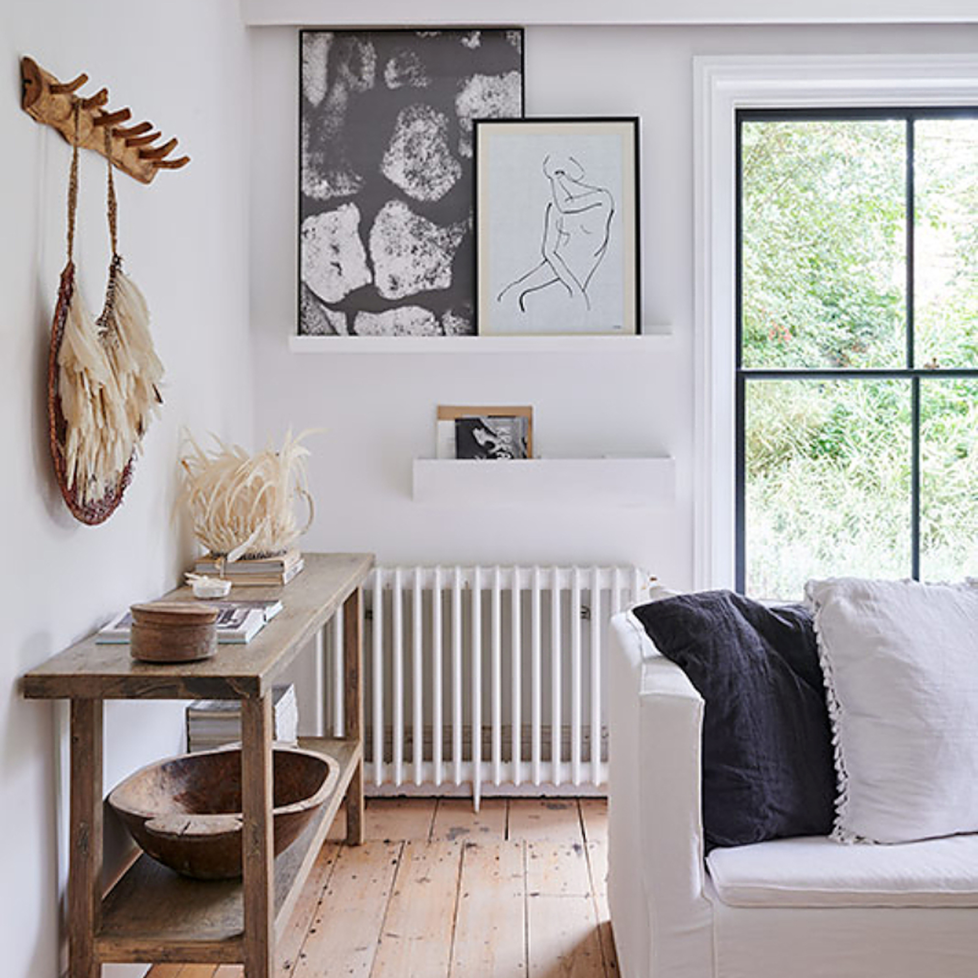a living room with white walls and wooden floorboards, with monochrome artworks and a white sofa