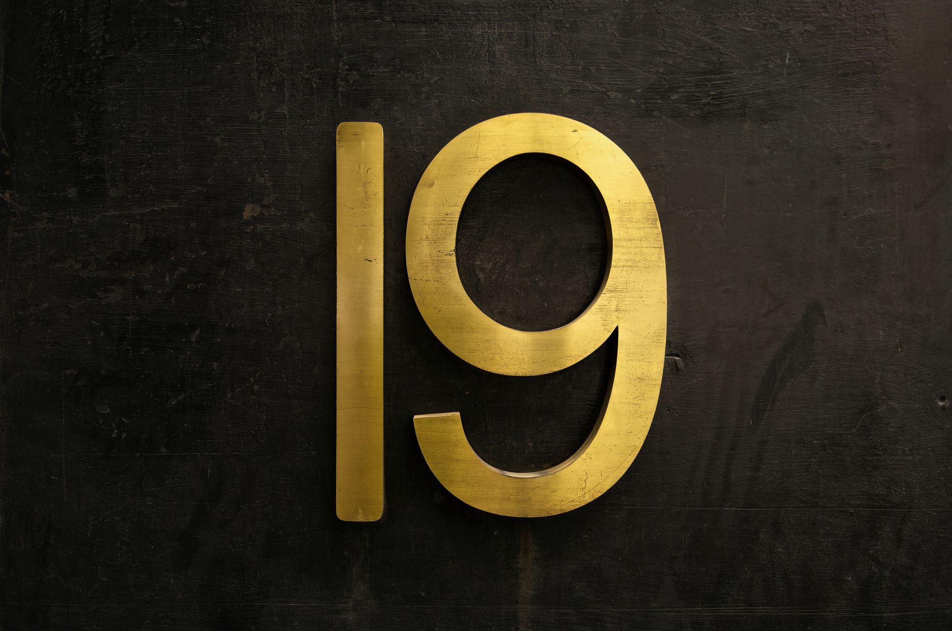 a golden and metallic number 19 on a dark background