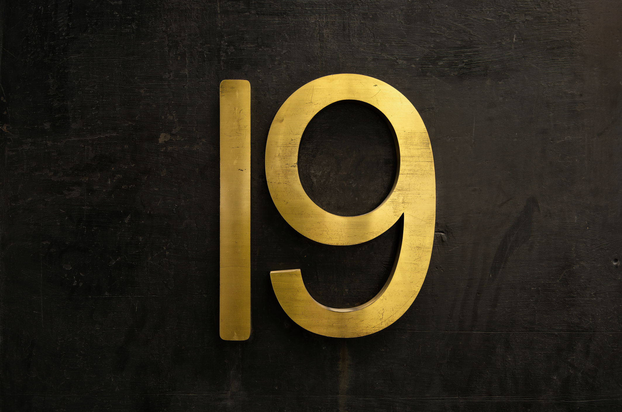 a golden and metallic number 19 on a dark background