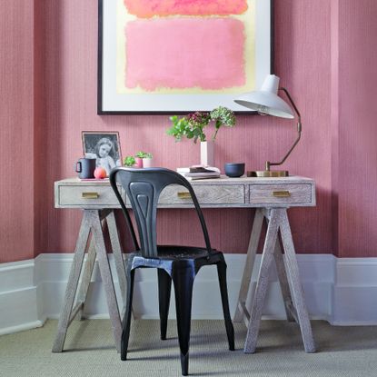 A home office with pink walls and a matching artwork on the wall