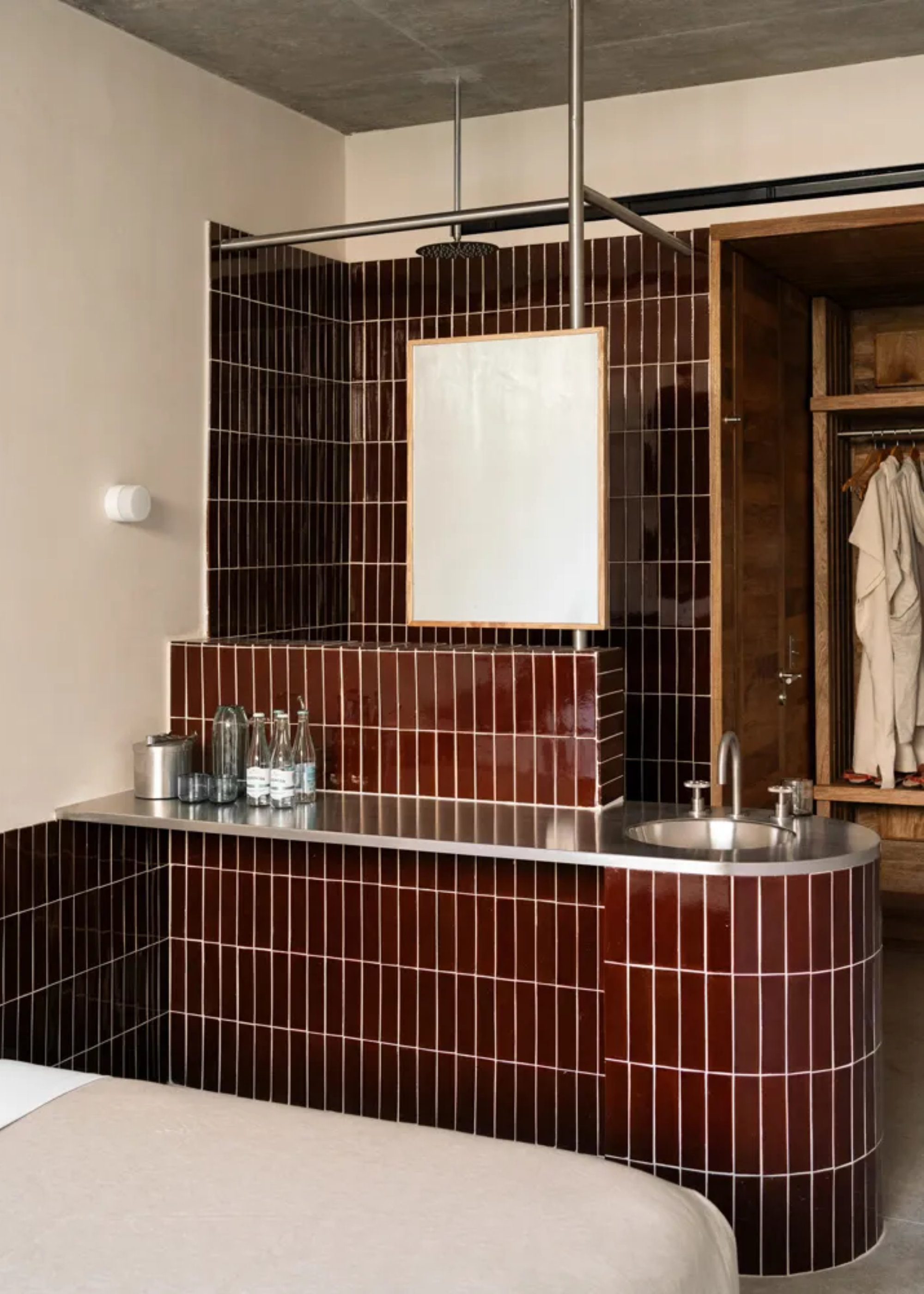 A brutalist, airy Mexican hotel pairs raw cement walls with glazed cherry plum tiles, hard chrome surfaces and geometric lines, and organic accents like exposed beams and rattan ceilings and wooden chairs.
