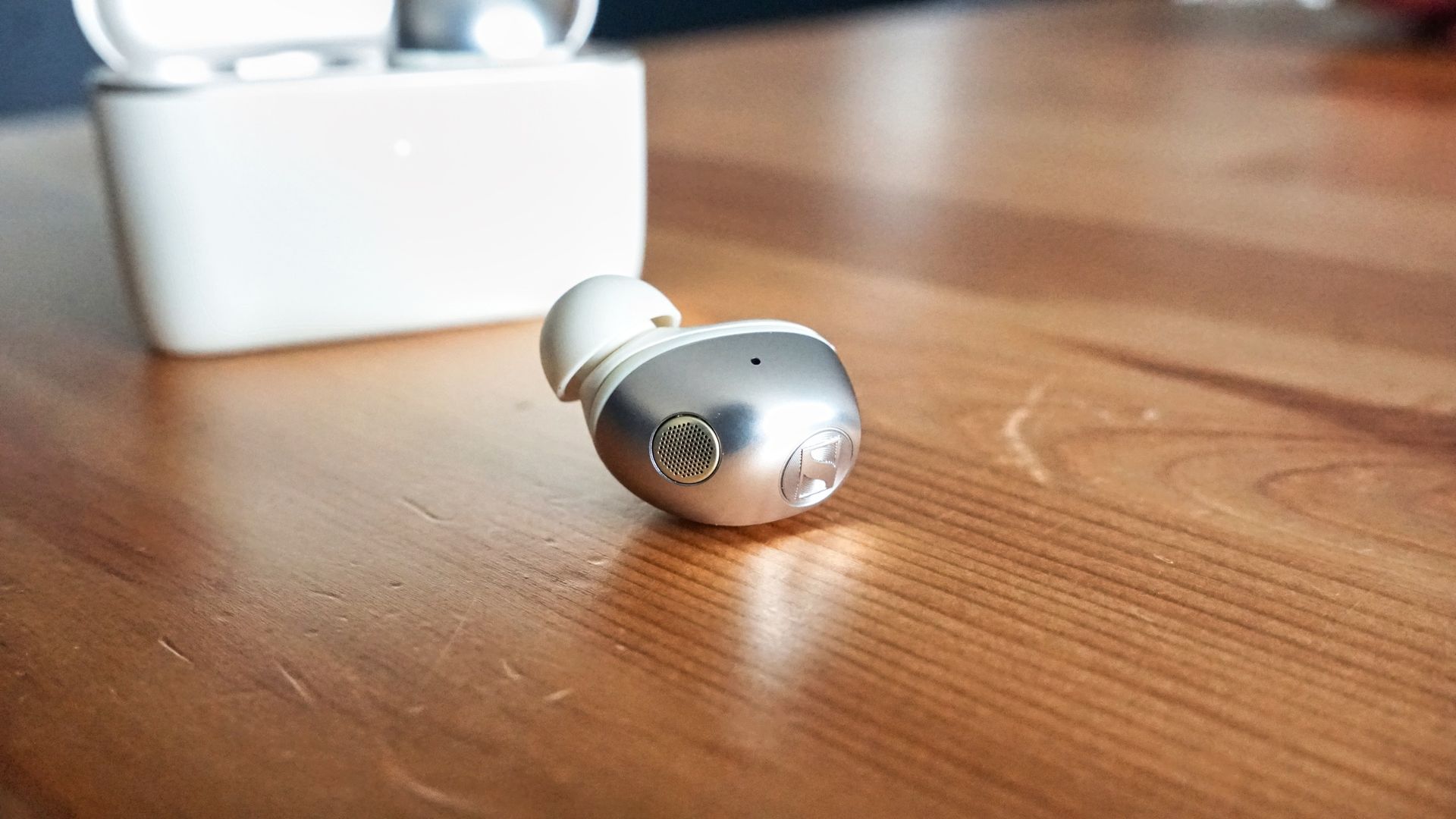 Sennheiser Momentum True Wireless 5 in white, showing details of the buds held in a hand