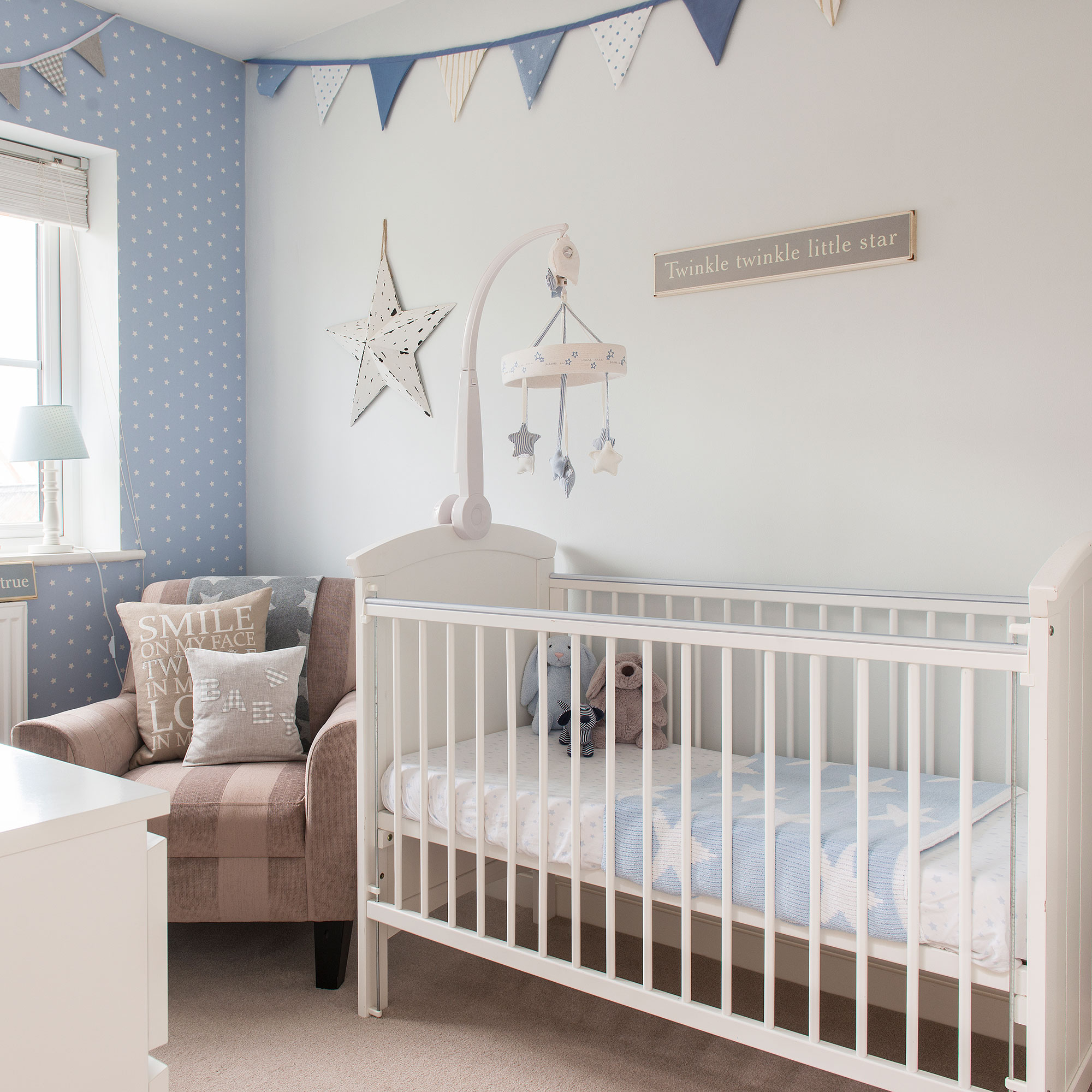 Nursery with white and blue walls, white crib and patterned bunting