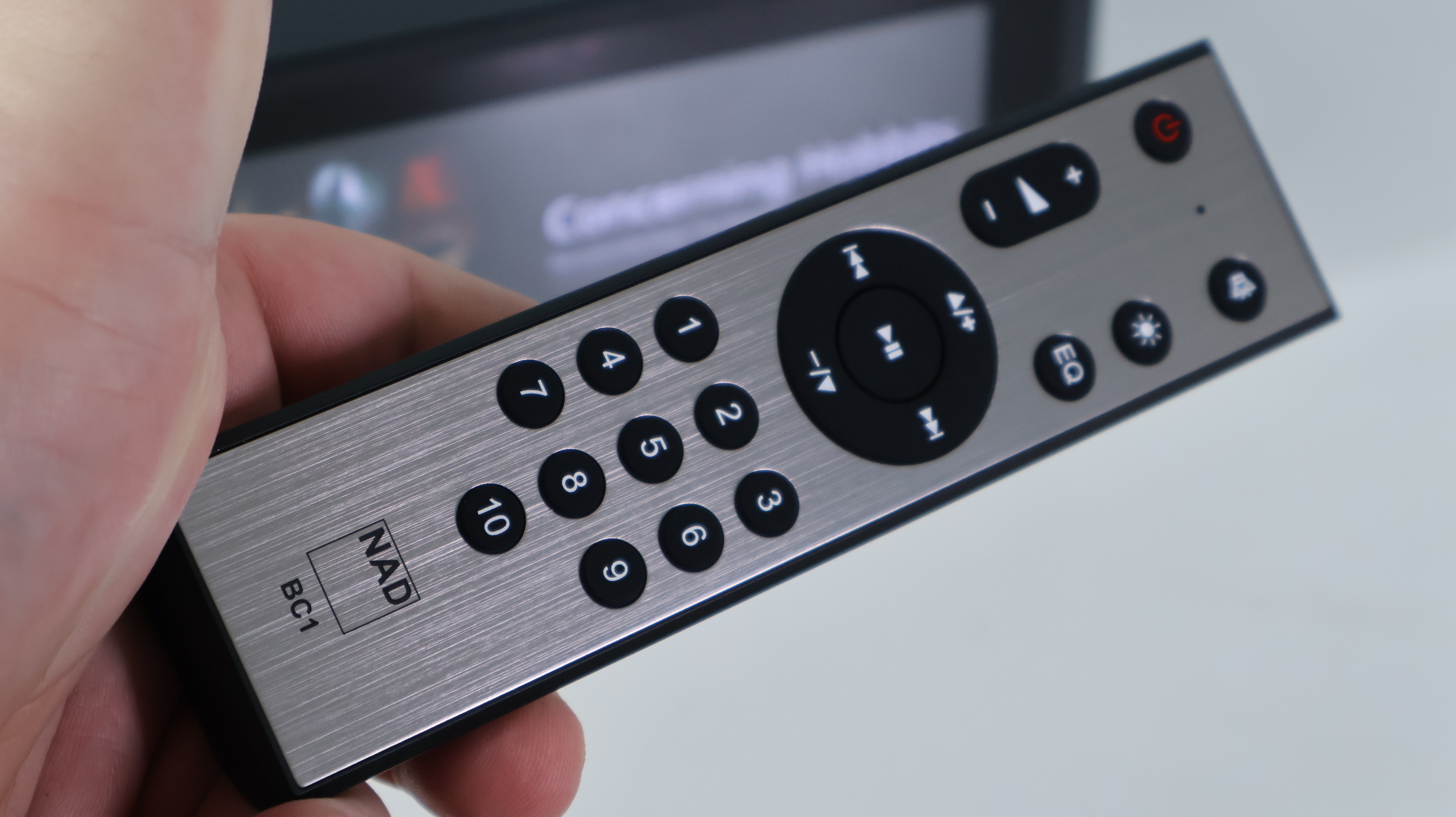 NAD M10 V3 remote control in a person's hand