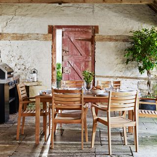 dining area with rustic wall wooden dinning table and chairs and stone block floor