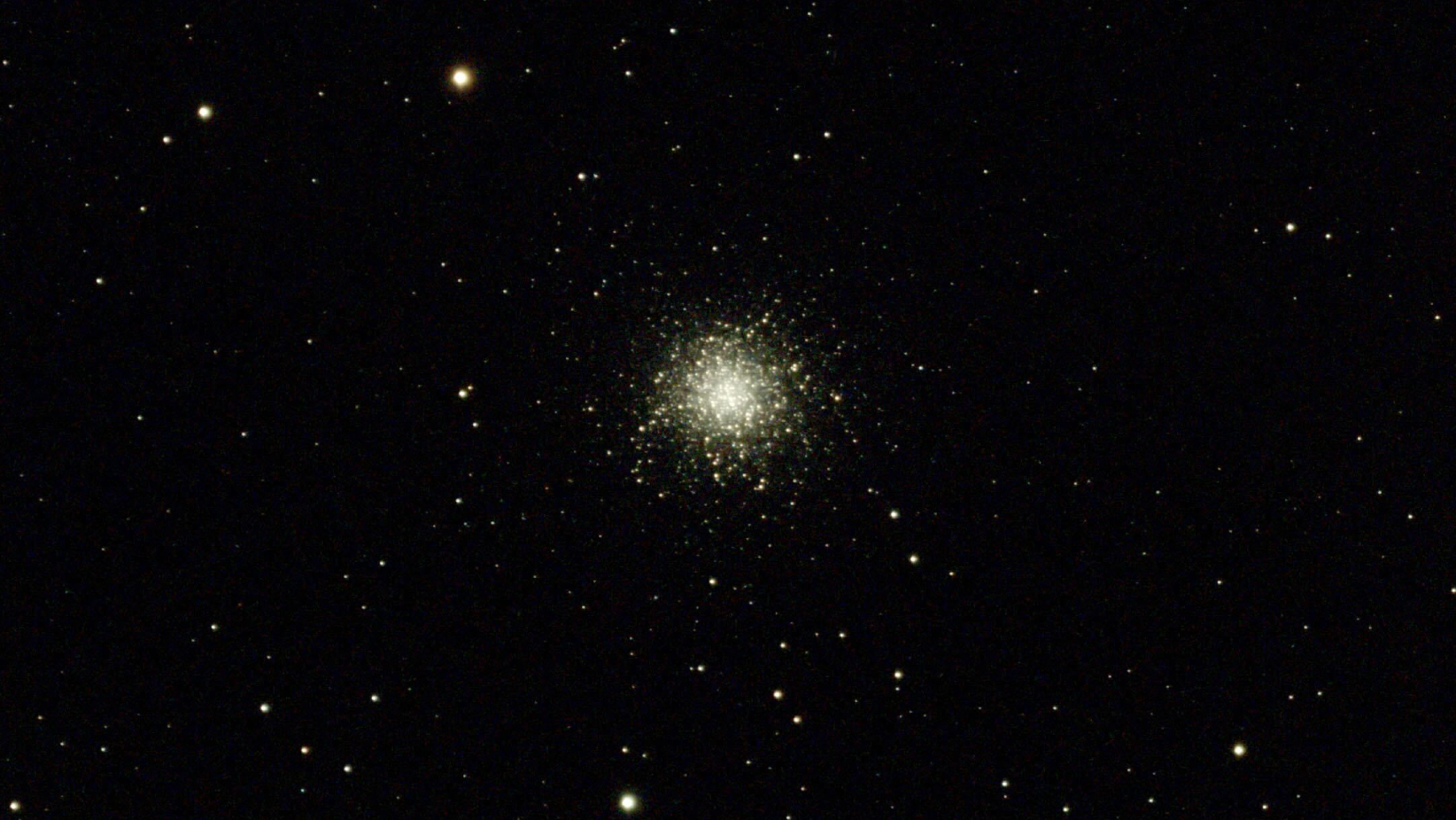 A dense spherical formation of tiny golden stars is visible in the centre of a black sky dotted with isolated stars.