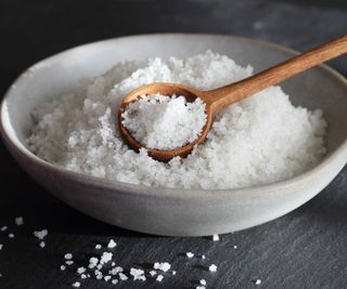 A white bowl of salt with a spoon