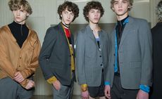 Four male models wearing clothing by Prada in various shades.