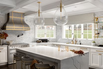 kitchen with marble island, large clear glass pendants, marble backsplash, open shelving, brass details, blinds 