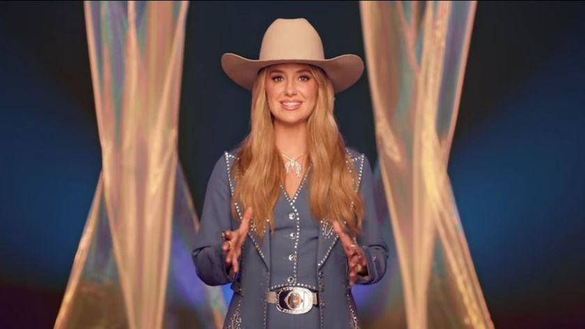 Host Lainey Wilson sports a bright smile and a cowboy hat as she faces the camera on stage at Nashville&#039;s Bridgestone Arena before the 59th Country Music Association Awards.