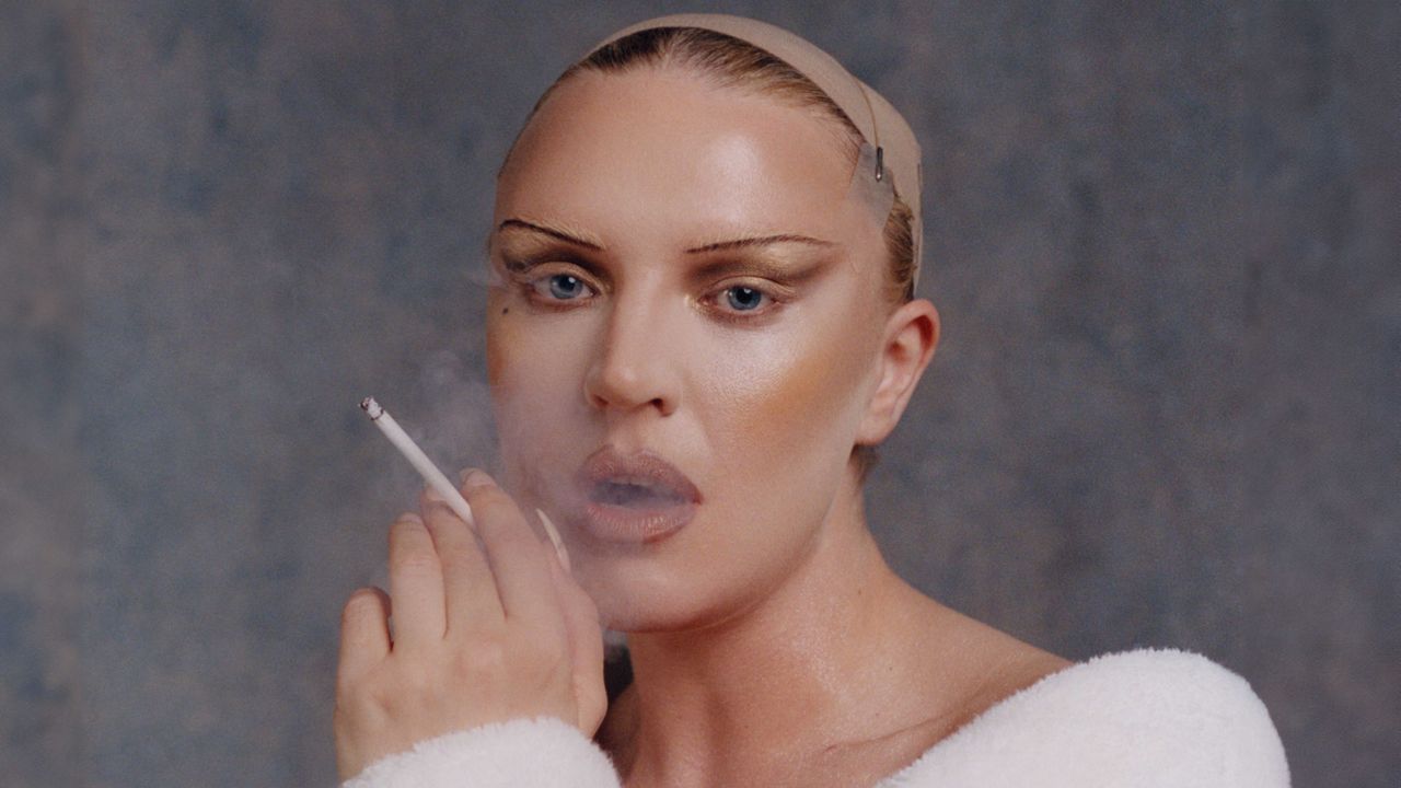 Self Esteem&#039;s Rebecca Taylor in a white robe smoking a cigarette