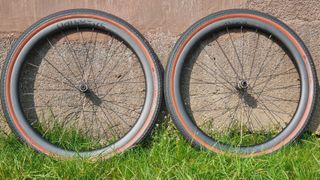 Two Parcours Alta 650B gravel wheels fitted with Hutchinson Touareg tyres, leaning against a wall on some grass