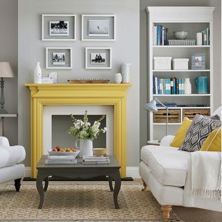 living room with yellow fireplace surround, grey walls and white bookcase, and cream armchair