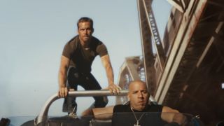 Vin Diesel driving a car off the cliff with Paul Walking on the top of the car in Fast Five.