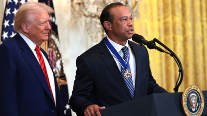 Tiger Woods speaks at a lectern next to President Trump
