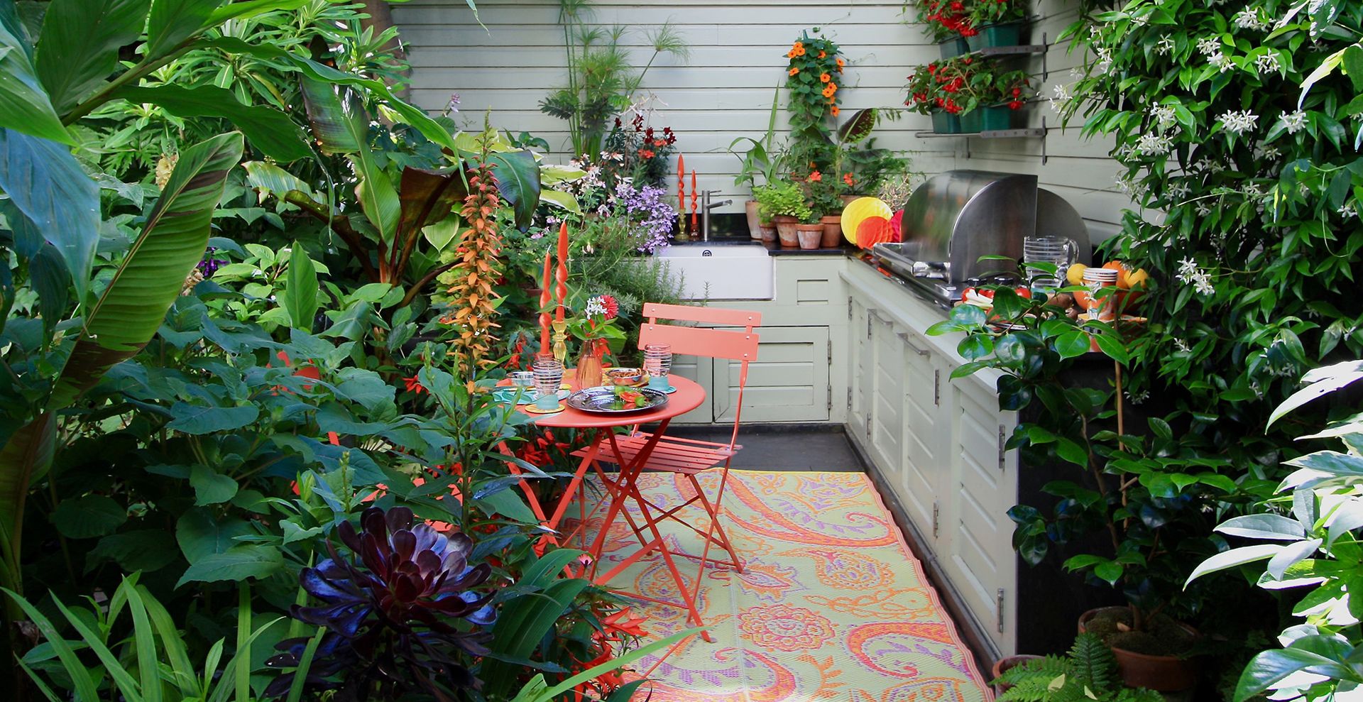 outdoor kitchen area with tropical plants and paisley outdoor rug