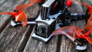 close up of the Emax Tinyhawk III drone camera on a wooden slatted surface