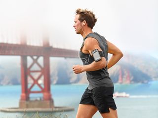 A man runs with his phone strapped to his arm.