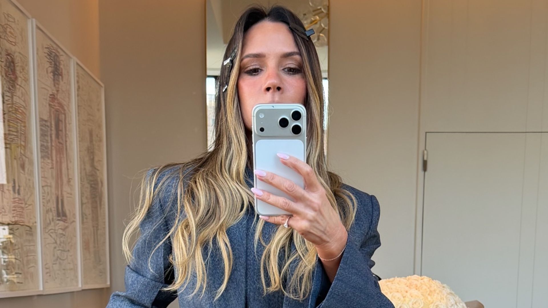 Victoria Beckham takes a mirror selfie wearing s dark grey three-piece suit with grey pointed-toe heels.
