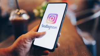 Jemand hält ein Smartphone in der Hand, auf dessen Display das Instagram-Logo zu sehen ist