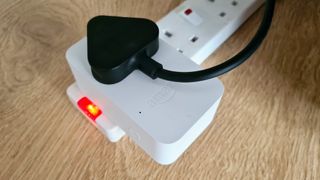 Amazon Smart Plug plugged in to power socket on wood floor