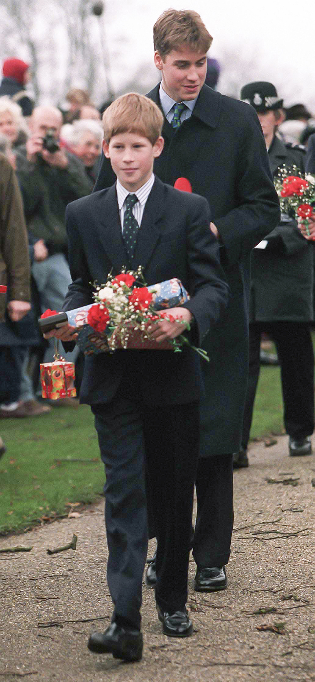 Prince Harry and Prince William holding gifts walking outside church on Christmas Day 1997