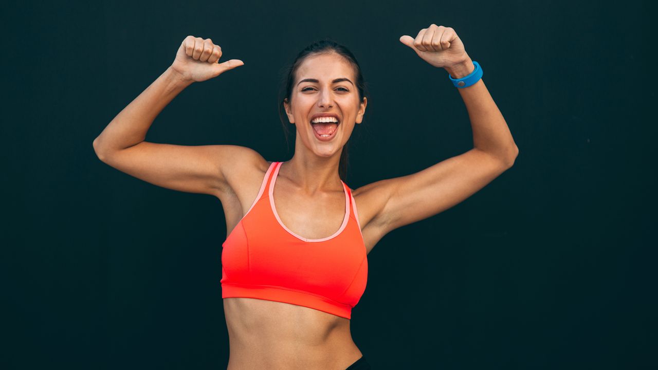 Woman raises her arms showing off a strong core 