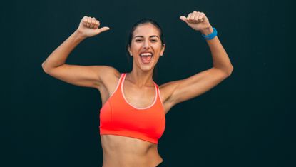 Woman raises her arms showing off a strong core 
