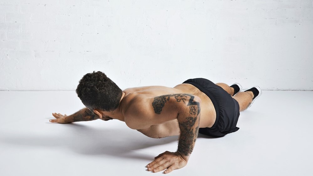 Man performing an archer push-up with his right arm extended