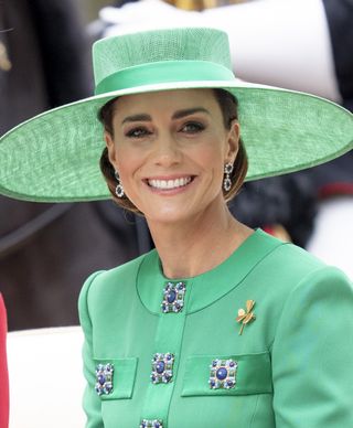 Kate Middleton attends Trooping the Colour in 2023 wearing a green jacket wide brim hat and gold pin