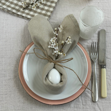 The finished napkin craft on a white plate, next to a knife and fork and water glass.