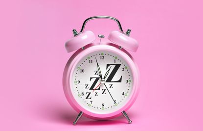 pink alarm clock with ZZzz on pink background