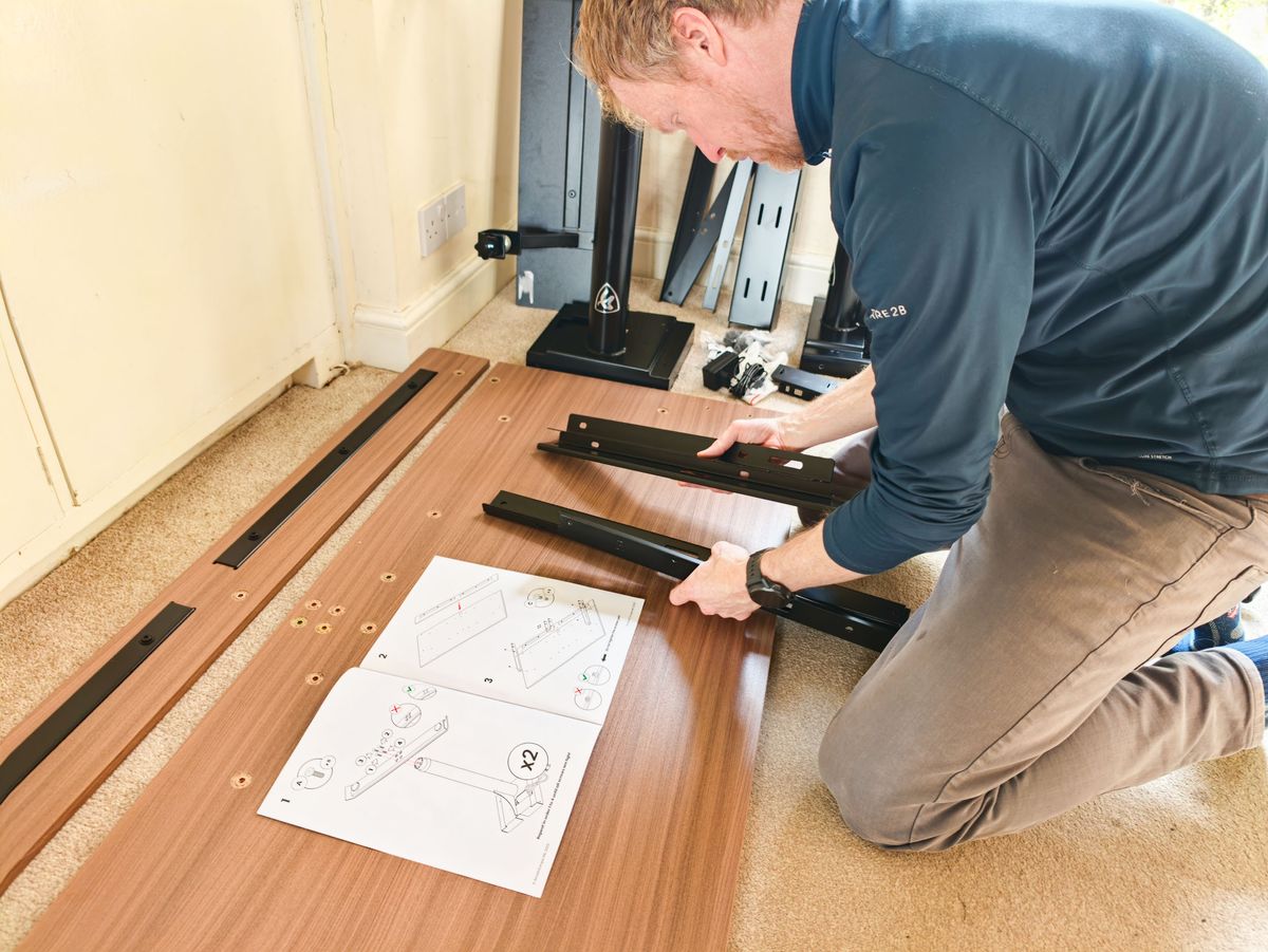 Man assembling the Arozzi Arena Nordico Electric Standing Desk
