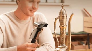 Smiling man scanning an ornament on his tablet with a 3D scanner