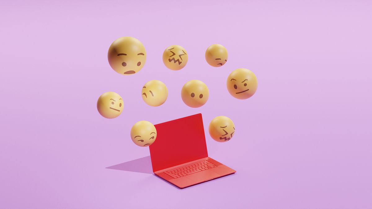 Conceptual image of a red laptop with 3D emojis floating around it with various expressions like shocked, sceptical, sad etc. Created on a purple background.