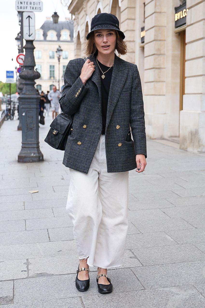 Keira Knightley wearing a bucket hat and gray coat with white pants and embellished Chanel Mary Janes in Paris