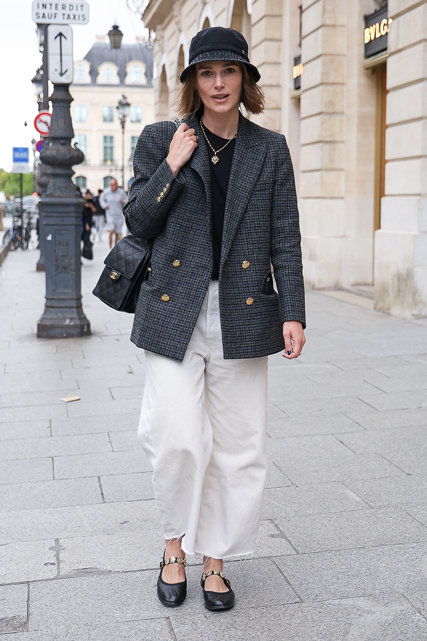 Keira Knightley wearing a bucket hat and gray coat with white pants and embellished Chanel Mary Janes in Paris