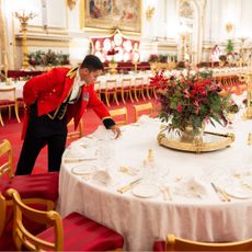 A butler fixing plates on a banquet table at Buckingham Palace