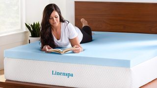 A woman with brown hair lies on top of a blue Linenspa 3 Inch Gel Infused Memory Foam Mattress Topper