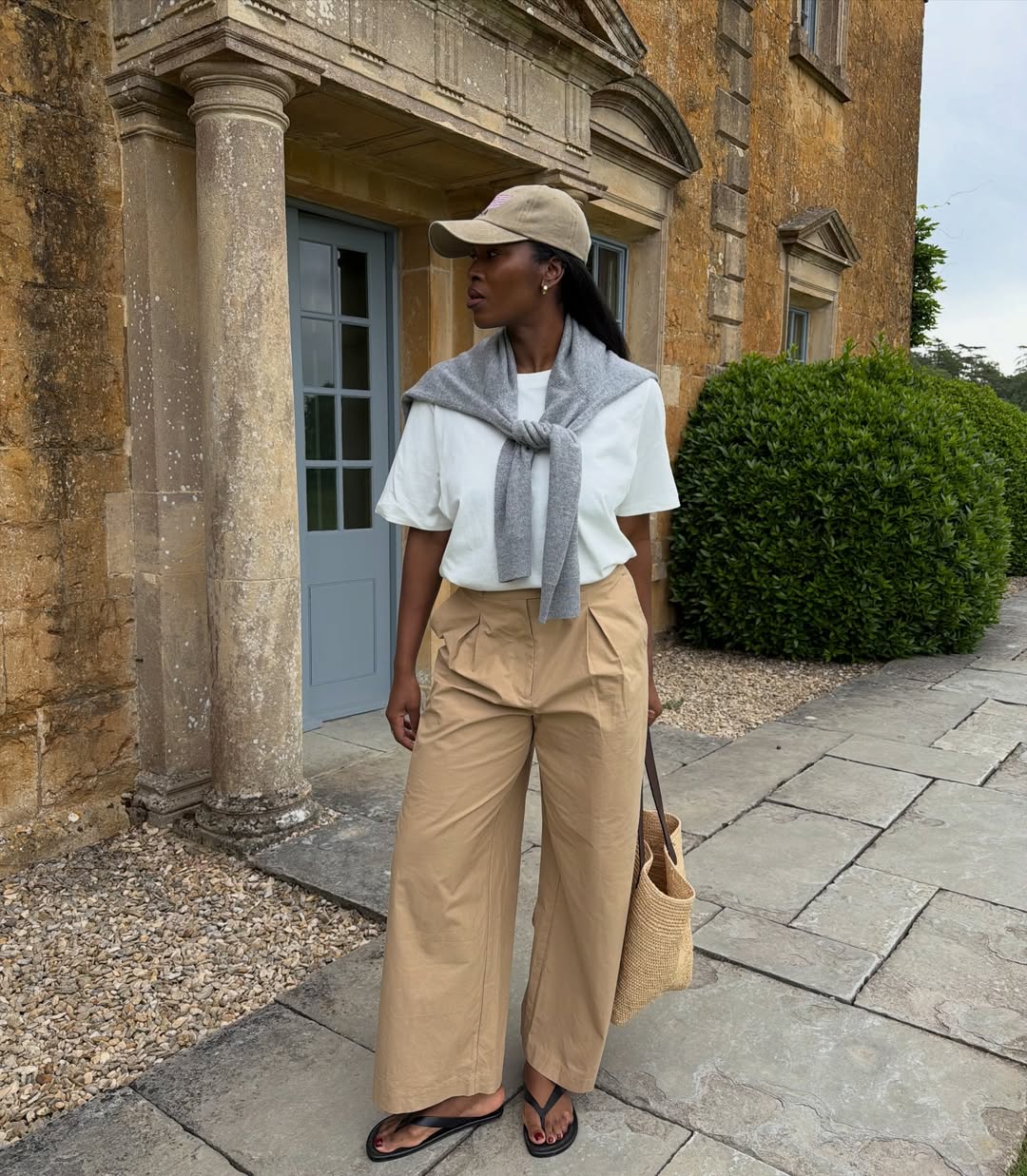 nlmarilyn wears a white tshirt, beige trousers, flip flops and a raffia basket bag