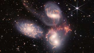 Three galactic swirls among stars against a black sky.