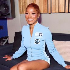 Keke Palmer with a pixie haircut. She is wearing a blue zip up top and smiling at the camera.