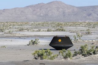 A black container with an orange spot sits in a desert landscape.