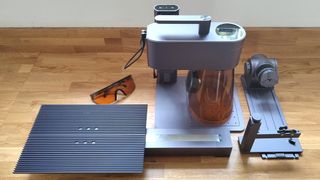 LaserPecker 4 review; a laser machine on a wooden table with an extension and rotary accessory