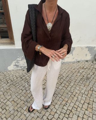 Fashion Director Hannah Lewis wearing a brown oversized shirt, drawstring trousers, and a statement pendant necklace