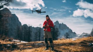 Man Flying Drone Against Mountains