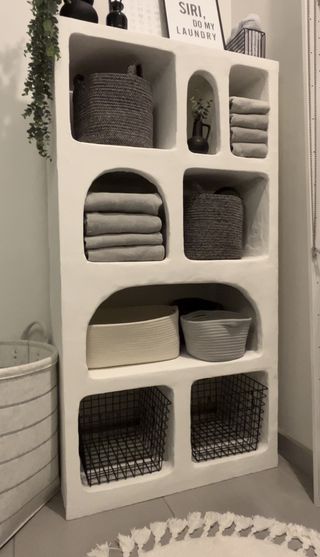 A customized shelf with rustic textured storage shelves housing folded laundry